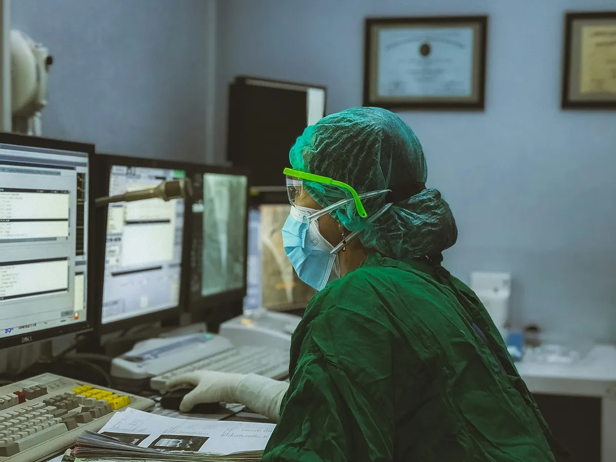 Clinician reviewing records at hospital computer workstations.